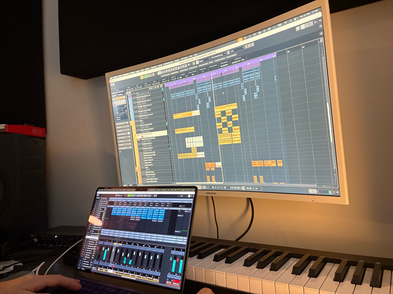 Ein Laptopbildschirm mit Schnittprogramm, dahinter ein E-Piano. Darüber an der Weand ist der Bildschirm des Laptops projeziert.